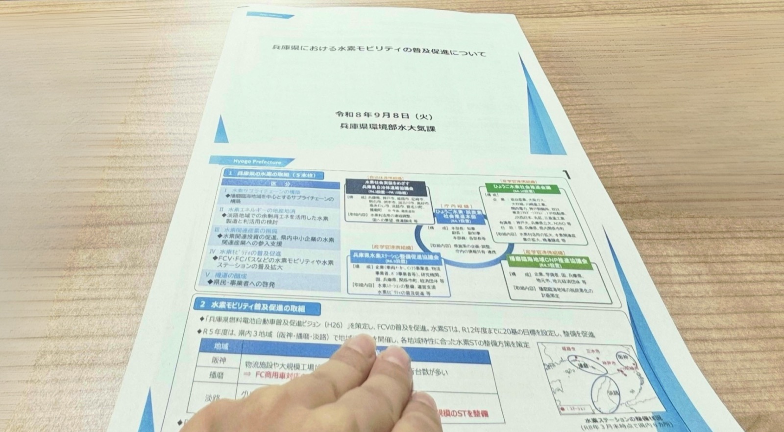 「兵庫県における水素モビリティの普及促進について」と題した兵庫県環境部水大気課の説明資料を指し示す手元