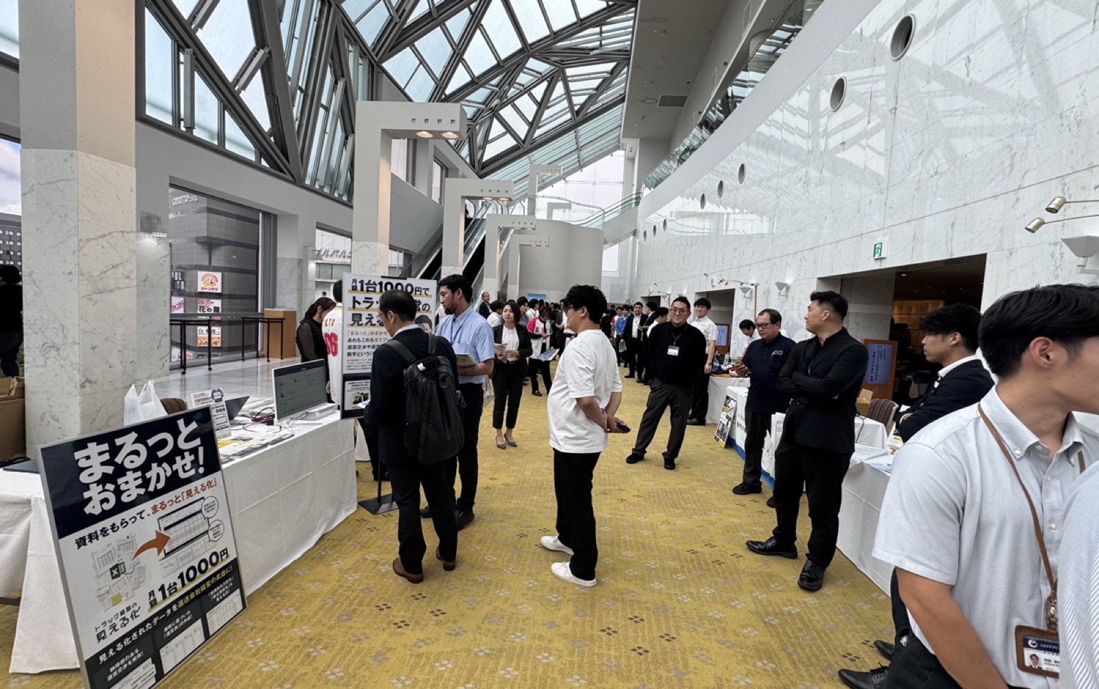全日本トラック協会青年部会 近畿ブロック大会の会場ロビーに並ぶ協賛企業のブースエリアと来場者